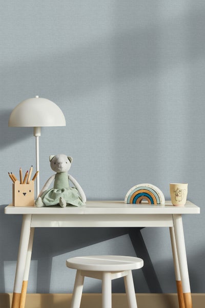 Heller Kinderzimmerbereich mit Schreibtisch, Hocker und Dekorationsgegenständen.