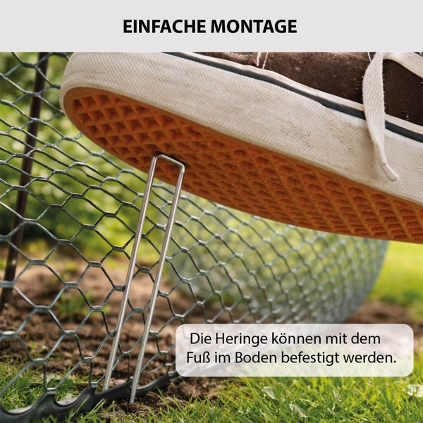 Ein metallener U-Hering wird mit dem Fuß im Erdboden fixiert, um einen Drahtzaun einfach zu befestigen.