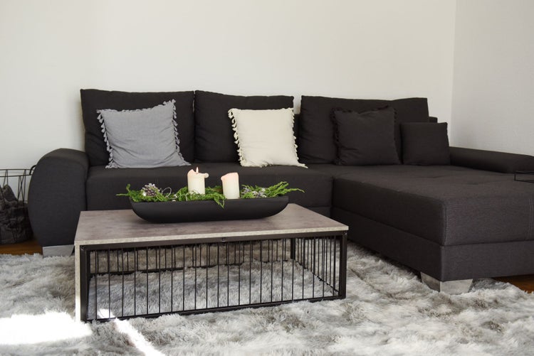 Modernes Wohnzimmer mit dunkelgrauem Sofa, Couchtisch im Industrial-Design und grauem Hochflorteppich.