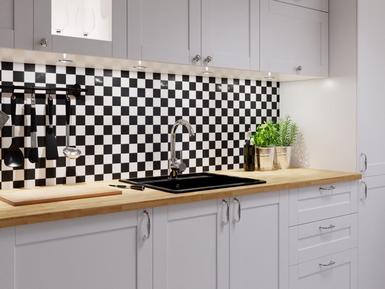 Moderne Küche mit schwarz-weiß kariertem Fliesenspiegel, schwarzer Spüle, Chrom-Armatur, Holz-Arbeitsplatte und grauen Schränken.