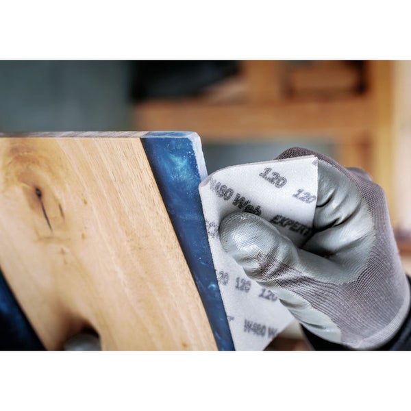 Schleifpapier der Körnung 120 wird zum Schleifen eines Werkstücks aus Holz und Epoxidharz verwendet.