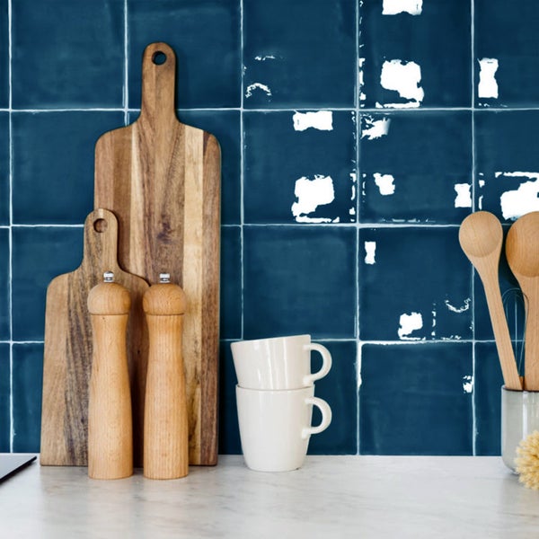 Quadratische Fliesen in einer Küche mit Küchenutensilien aus Holz und einer weißen Tasse auf einer Arbeitsplatte
