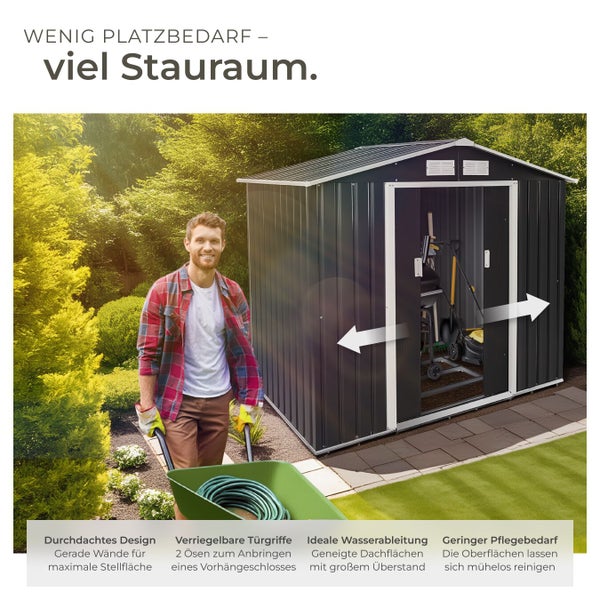 Ein Mann mit Schubkarre vor einem dunkelgrauen Metall-Gartenhaus in einem hellen Garten. Mit Schiebetüren, viel Stauraum und verriegelbaren Griffen.