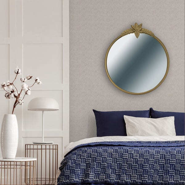 Schlafzimmer mit Bett, Nachttischen, Lampe, Vase mit Baumwollzweigen und einem runden Spiegel mit Zierrahmen