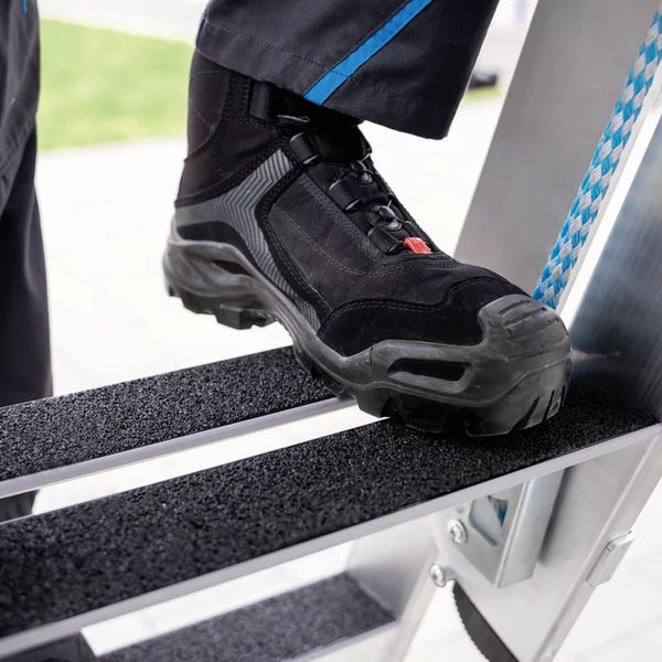 Person mit Sicherheitsschuh auf einer Leiter