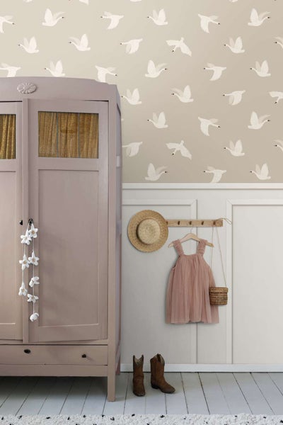 Vliestapete mit Schwanenmuster in einem Kinderzimmer mit Holzschrank, Wandpaneelen, Strohhut, Kinderkleid und Stiefeln.