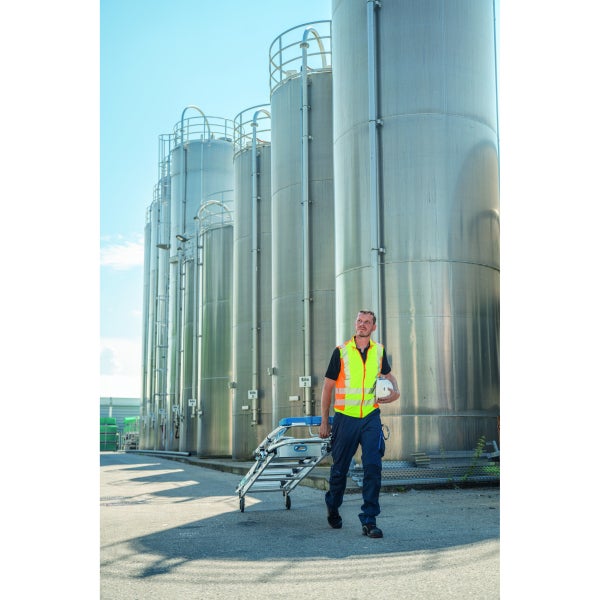 Ein Mann zieht eine fahrbare Arbeitsbühne vor Silos.