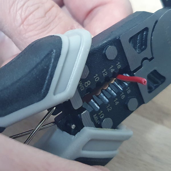 Abisolierzange im Einsatz beim Abmanteln eines Kabels mit Skalierung für verschiedene Kabelquerschnitte.