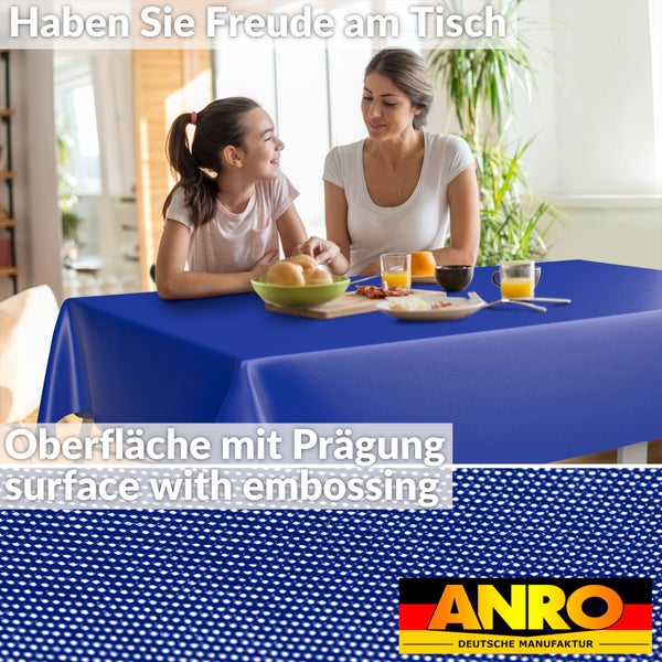 Abwaschbare Tischdecke mit geprägter Oberfläche auf einem gedeckten Tisch mit zwei Personen in einem hellen Zimmer. ANRO Deutsche Manufaktur Logo.