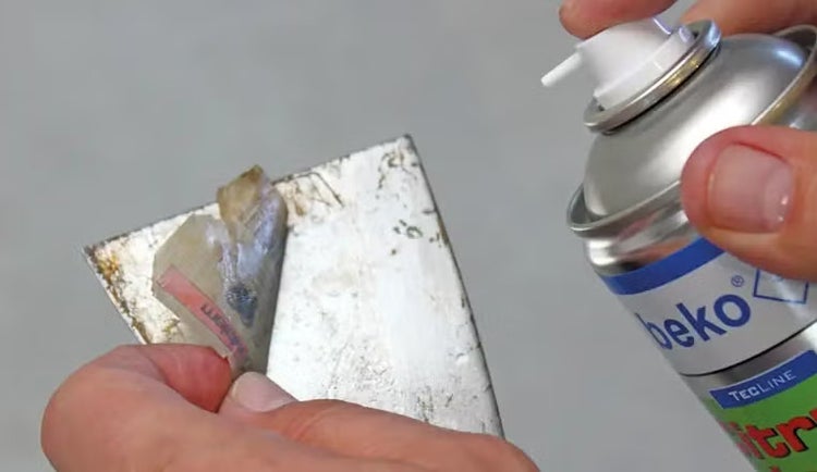 Reinigung eines Metallspachtels von Aufkleberresten mit beko Citrusreiniger Spray.