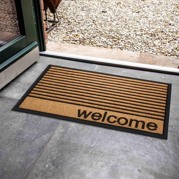Fußmatte mit Willkommensaufschrift vor einer Haustür