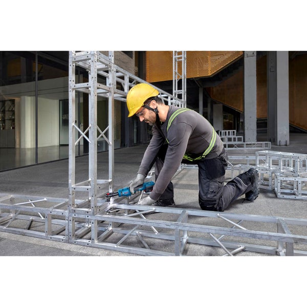 Ein Mann mit Schutzhelm montiert eine Aluminiumkonstruktion mit einem Elektroschrauber.