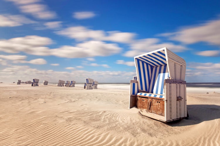 Strandkörbe am Sandstrand unter blauem Himmel