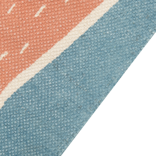 Detailansicht eines flachgewebten Teppichs in Blau und Terracotta mit weißem Trennstreifen und grober Struktur.