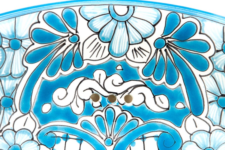 Detailansicht eines Keramikwaschbeckens mit floralem Muster und Überlauflöchern