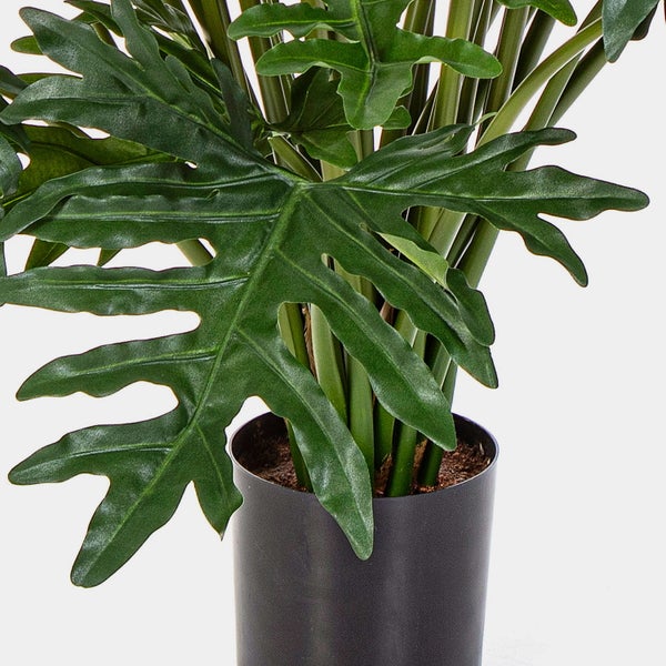 Künstliche Philodendron-Pflanze mit großen, tief gelappten Blättern im schwarzen Topf.