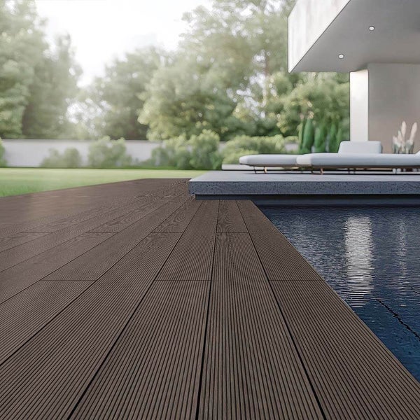 Moderne Terrasse mit dunkelbraunen Terrassendielen am Pool, Garten und Liegestühle im Hintergrund.