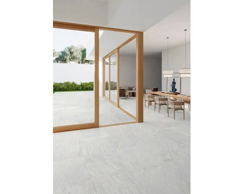 Heller Raum mit Fliesenboden, Esstisch und Zugang zum Garten durch Schiebetüren