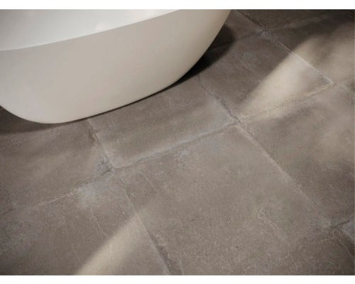 Detailaufnahme von grauen Bodenfliesen neben einem Badewannenrand