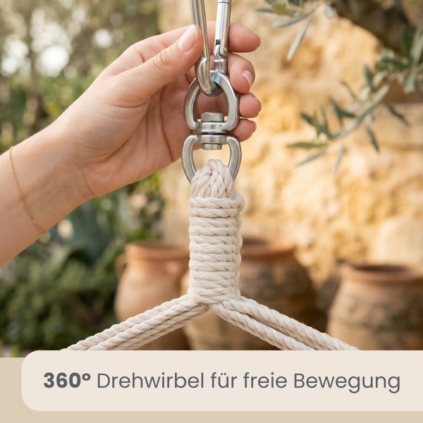 Hand befestigt Karabiner an einem 360 Grad Drehwirbel aus Metall für Hängesessel an einem Seil.