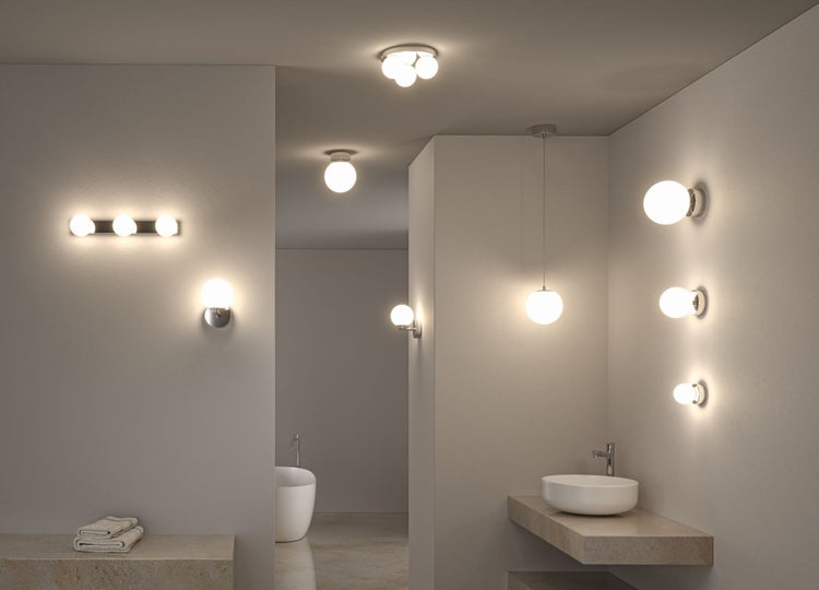 Modernes Badezimmer mit verschiedenen kugelförmigen Wand- und Deckenleuchten, einem Waschbecken und einer freistehenden Badewanne.