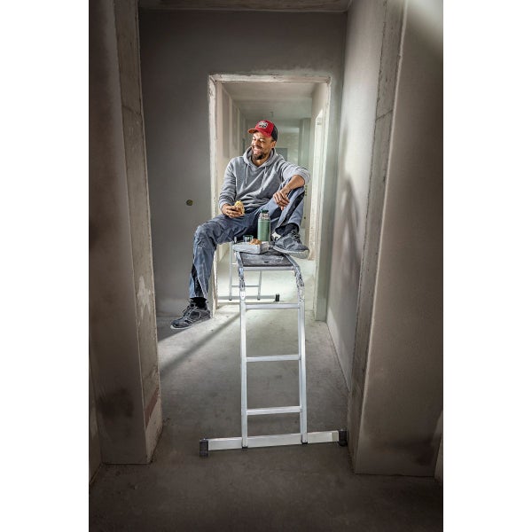 Handwerker sitzt auf einer Aluminium-Arbeitsbühne und macht eine Pause in einem Rohbau