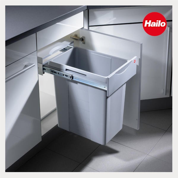 Hailo Logo. Ein graues Abfallsystem zum Ausziehen, eingebaut in einen weißen Küchenunterschrank mit Metallschienen.