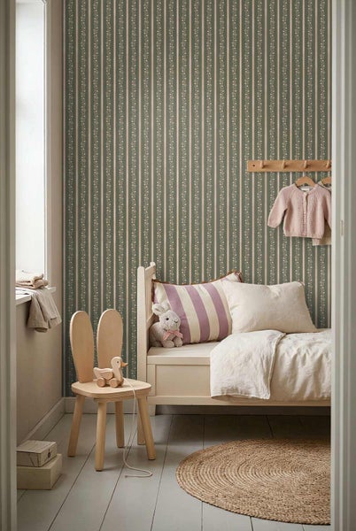 Gemütliches Kinderzimmer mit gestreifter Tapete mit Blumenmuster, einem Kinderbett aus Holz, einem Hasenohr-Stuhl und einem Jute-Teppich.
