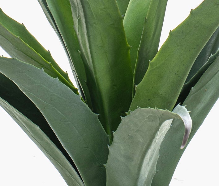 Detailaufnahme eines künstlichen Pflanzenstiels mit verzweigten Ästen und grünen Blättern.