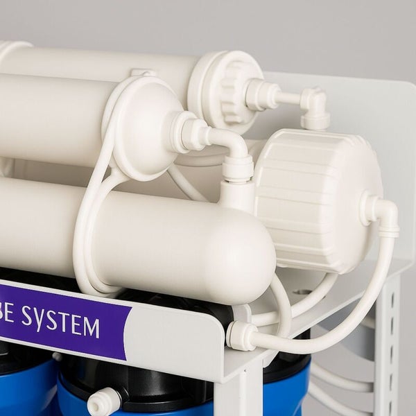 Detailansicht eines mehrstufigen Wasserfiltersystems mit weißen und blauen Filtergehäusen sowie Verbindungsschläuchen.