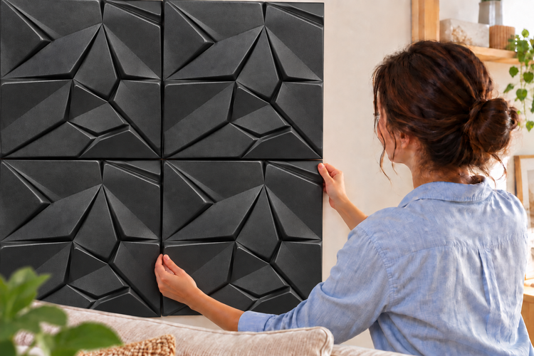 Frau montiert geometrische 3D Wandpaneele als Wandverkleidung im Wohnzimmer.