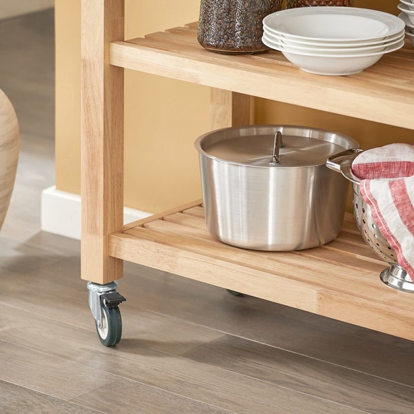 Detailansicht eines Küchenwagens mit Holzregalen und Rollen, beladen mit einem Edelstahltopf mit Deckel, einem Sieb und Geschirr.
