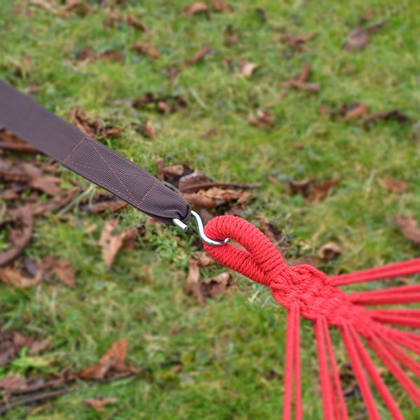 Hängemattenbefestigung mit braunem Gurtband, S-Haken aus Metall und roter Seilschlaufe im Garten auf einer Rasenfläche.