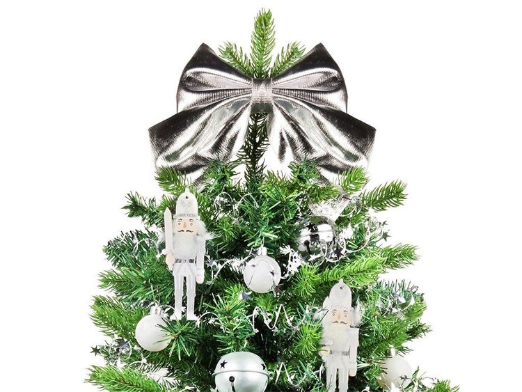 Weihnachtsbaumspitze in Form einer glänzenden Schleife auf einem geschmückten künstlichen Tannenbaum mit Nussknackerfiguren und Kugeln