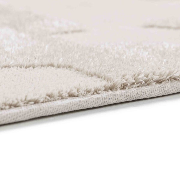 Nahaufnahme eines beigen Hochflor-Teppichs mit Textur und gewebtem Rücken.