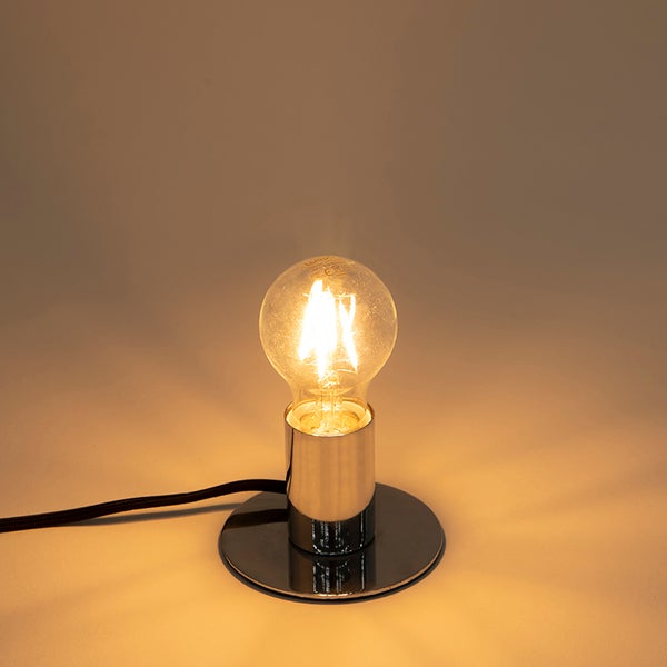 Tischleuchte mit verchromtem Metallsockel und eingeschaltetem LED-Filament-Leuchtmittel.