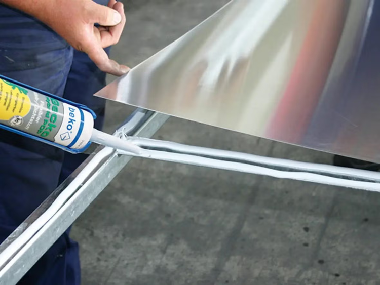 Handwerker beim Auftragen von beko Hybrid POP Dichtstoff auf ein Metallprofil für die Verklebung einer Metallplatte.