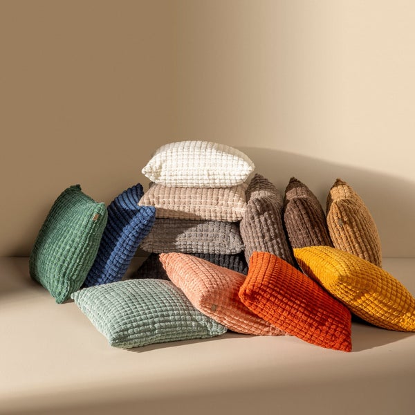 Stapel dekorativer Kissen in verschiedenen Farben und Texturen