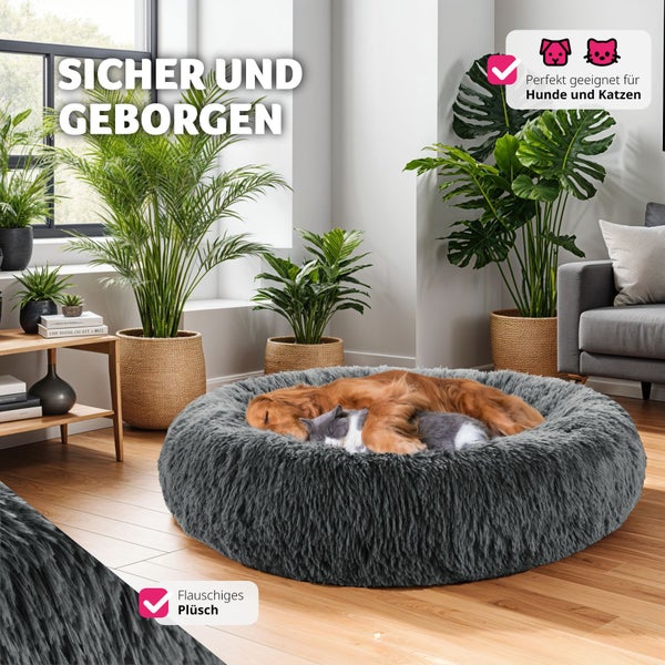 Ein Hund und eine Katze schlafen auf einem runden, grauen, flauschigen Haustierbett in einem Wohnzimmer.