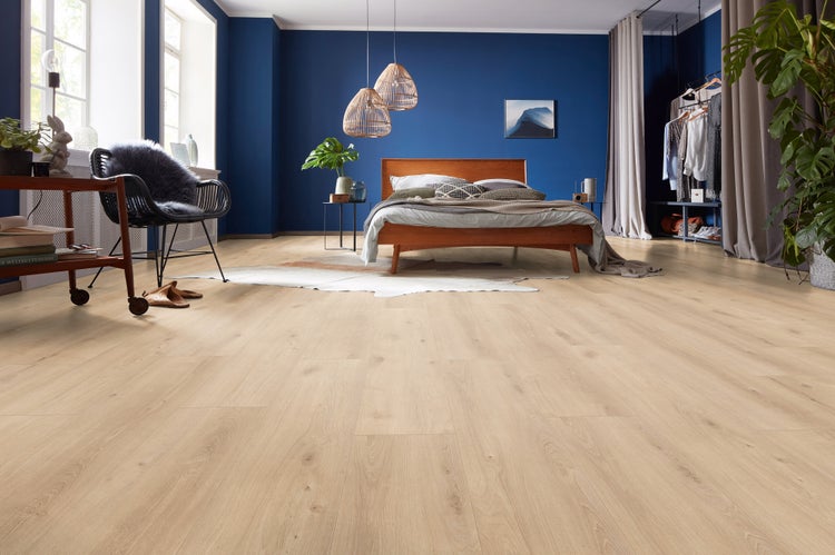 Helles Laminat in Holzoptik in einem modern eingerichteten Schlafzimmer mit dunkelblauen Wänden und Holzmöbeln.
