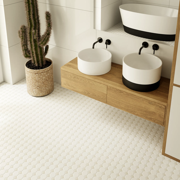 Helles Badezimmer mit zwei runden Aufsatzwaschbecken auf einem hölzernen Waschtisch, schwarzen Wandarmaturen, Mosaikboden und einem Kaktus.