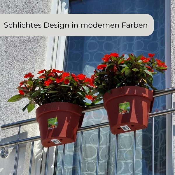 Zwei braune Balkonkästen mit roten Blumen und grünen Blättern hängen an einem Geländer.