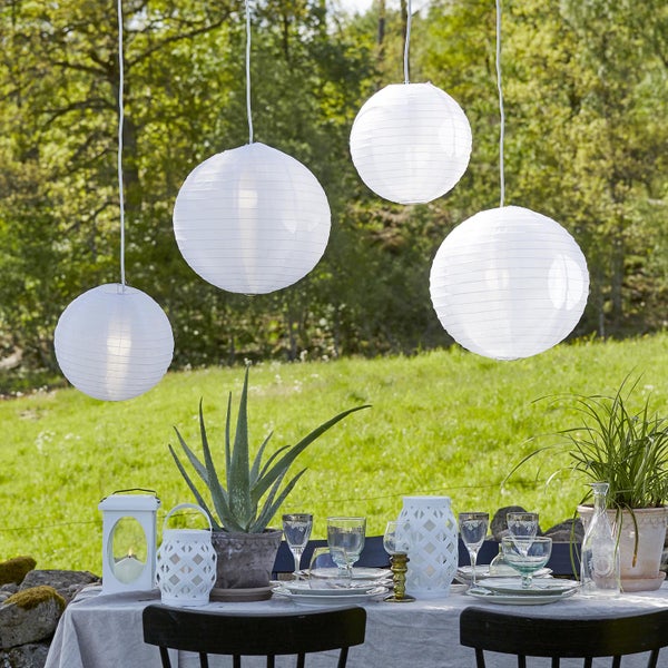 Szene mit gedecktem Tisch im Freien und vier hängenden Papierlaternen