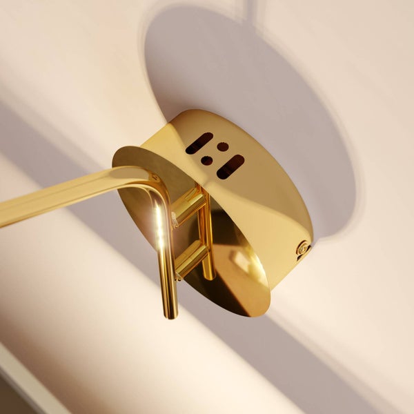 Nahaufnahme einer runden Wandhalterung einer Lampe in glänzender Goldoptik mit Aussparungen.