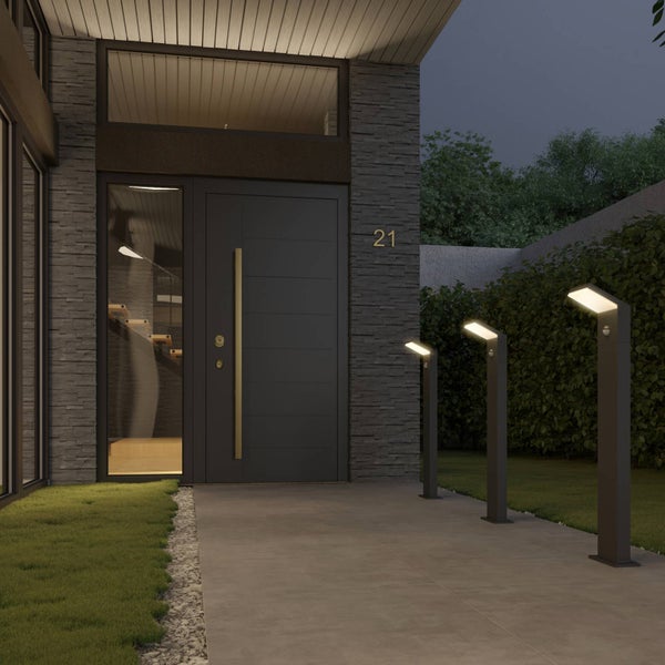 Moderne LED-Wegeleuchten mit Bewegungsmelder beleuchten einen Gehweg vor einem Hauseingang mit Steinfassade.