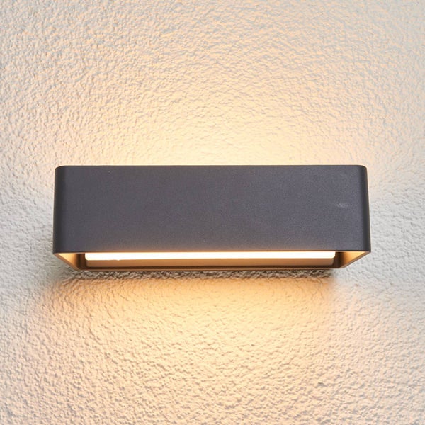 Rechteckige Außenwandleuchte in Anthrazit mit Lichtaustritt nach oben und unten an einer strukturierten Wand.