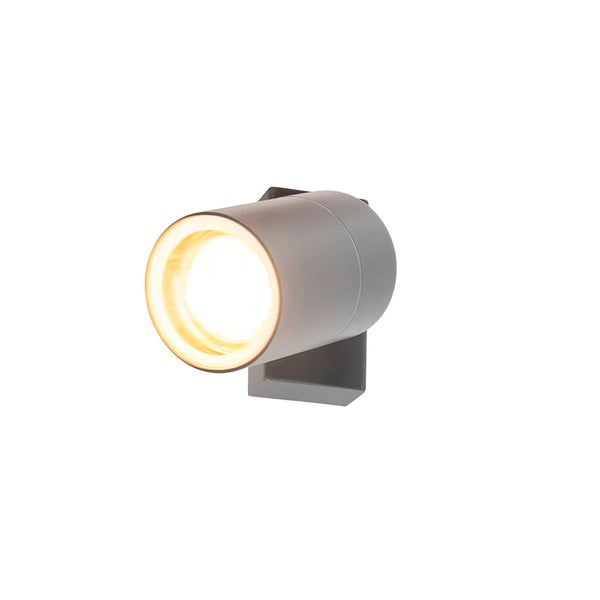 Grauer Wandstrahler in zylindrischer Form mit eingeschalteter Lichtquelle für den Außenbereich.