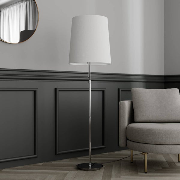 Stehlampe mit Stoffschirm neben Sessel und Spiegel