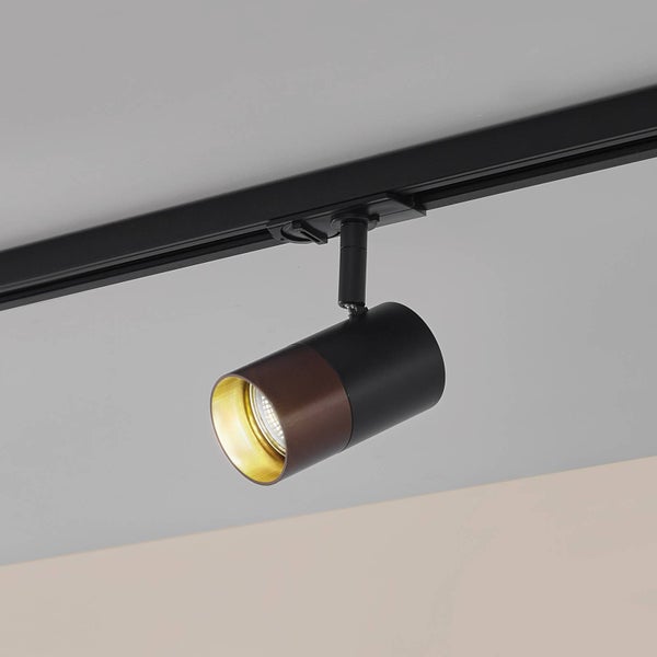 Schwarzer Schienenstrahler mit braunem Ring und goldener Innenseite montiert an einer schwarzen Stromschiene.