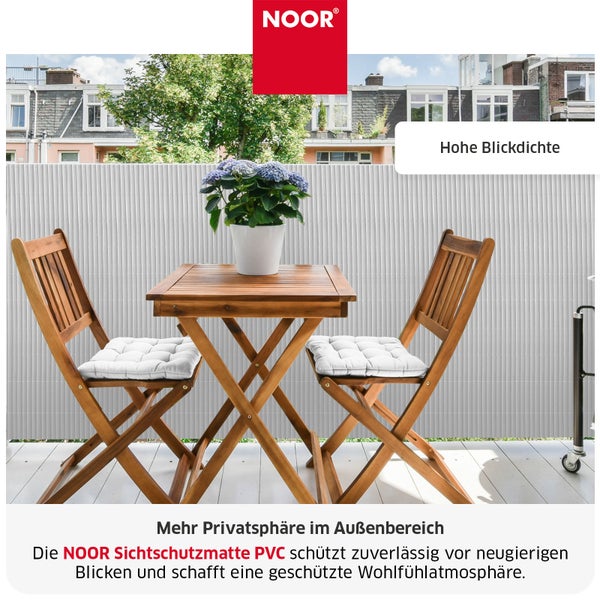 Noor Logo Sichtschutzmatte aus PVC als Balkonverkleidung mit hohem Sichtschutz auf einem Balkon mit Holzstühlen und Holztisch.